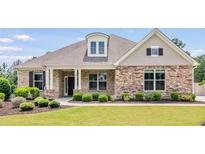 Charming single-story home with a stone facade, well-manicured lawn, and lovely landscaping at 1374 Highland Wood Ct, Auburn, GA 30011