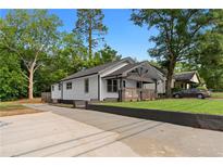 Charming renovated home with a fresh white exterior, landscaped yard, and long driveway at 2209 Browns Mill Se Rd, Atlanta, GA 30315