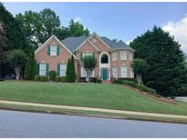 Traditional two-story brick home with green shutters, manicured lawn, and mature trees at 1564 Stepstone Way, Lawrenceville, GA 30043
