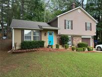 Charming two-story home with a well-maintained lawn, tidy landscaping, and a bright blue front door at 4678 Browns Mill Ferry Rd, Lithonia, GA 30038