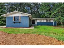 Charming brick home with a manicured lawn and mature trees, featuring unique window details at 4756 Fellsridge Dr, Stone Mountain, GA 30083