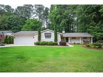 Charming single-story home boasts a lush lawn, complemented by manicured landscaping and a swing on the inviting front porch at 3850 Beya Way, Atlanta, GA 30340