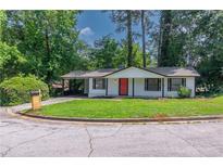 Charming single-story home featuring a well-manicured lawn, complemented by a bright red front door and a covered carport at 4922 Glenside Ct, Stone Mountain, GA 30088