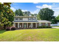 Charming two-story home featuring a covered front porch with rocking chairs and a lush green lawn at 385 Stonebridge Trl, Roswell, GA 30075