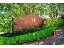 Brick entrance to Heritage Place condominium complex with lush landscaping and mature shade trees at 211 Colonial Homes Nw Dr # 2304, Atlanta, GA 30309