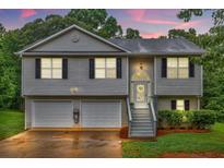 Charming split-level home featuring a two-car garage and inviting front porch at sunset at 240 Mountain Ln, Covington, GA 30016