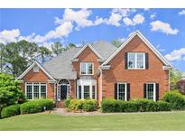 Traditional brick home featuring a manicured lawn, mature landscaping, and a symmetrical facade with classic architectural details at 13090 Magnolia Crescent Dr, Roswell, GA 30075