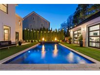Stunning backyard pool featuring elegant water features, manicured landscaping, and ambient lighting at 7165 Cordery Rd, Cumming, GA 30040