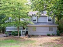 Charming two-story home with gray siding, front porch, and lush green trees surrounding the property at 219 Park Avenue, Woodstock, GA 30188
