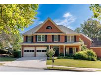 Charming two-story brick home features a two-car garage and well-manicured landscaping at 4729 Woodland Brook Se Ct, Atlanta, GA 30339