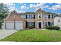 Traditional brick home with a two-car garage and a well-manicured front lawn at 148 Crystal Downs Way, Suwanee, GA 30024