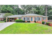 Charming brick home featuring a lush front yard, a carport and blue shutters at 1744 Chateau Dr, Dunwoody, GA 30338