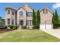 Beautiful two-story brick home featuring a manicured lawn, trimmed shrubbery, and a two-car garage at 3717 Shady Maple Dr, Stonecrest, GA 30038