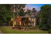 Elegant brick home featuring a covered porch, lush landscaping, and mature trees at twilight at 3750 Maryhill Nw Ln, Kennesaw, GA 30152