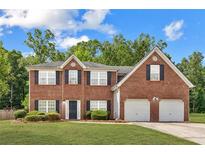 Charming two-story brick home with a well-manicured lawn and attached two-car garage at 1955 Pius Dr, Ellenwood, GA 30294
