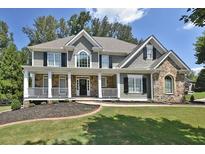 Charming two-story home with a manicured lawn, inviting front porch, and stone accents at 6425 Riley Manor Way, Cumming, GA 30028