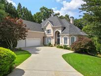 Stately home with a three-car garage and elegant circular driveway surrounded by mature trees and lush landscaping at 9745 Autry Falls Dr, Alpharetta, GA 30022