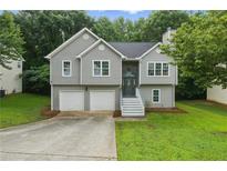 Charming home with gray siding, stone accents, two-car garage and well-maintained lawn at 11020 Knotty Pine Pl, Hampton, GA 30228