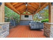 Outdoor lounge with hanging porch swings, a built-in bar, mounted television, and wood beamed ceiling at 4030 River Ridge Se, Marietta, GA 30067