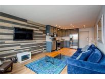 Open living area with a flat screen tv, wood feature wall, blue couch, and stainless steel kitchen at 215 Piedmont Ne Ave # 804, Atlanta, GA 30308