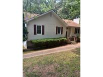 Charming single-story home featuring beige siding, red shutters, landscaped yard, and inviting front porch at 291 N Briar Rdg, Woodstock, GA 30189