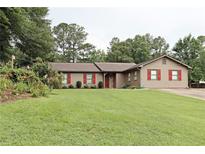 Charming single-story home with a well-manicured lawn, colorful landscaping, and inviting red shutters and door at 199 Candy Ln, Canton, GA 30115