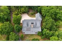 Stunning aerial view of a grey roofed home nestled among lush trees, featuring a long porch and driveway at 2216 Trammel Rd, Cumming, GA 30041