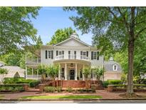 Charming two-story traditional home featuring a brick porch with columns and double-decker balconies nestled in a lush landscape at 8643 Ellard Dr, Alpharetta, GA 30022