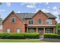 Charming brick home featuring well-maintained landscaping and inviting covered front porch with classic shutters at 435 Ruby Forest Pkwy, Suwanee, GA 30024
