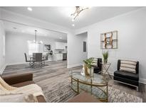 Open-concept living and dining area with modern light fixtures and gray wood flooring at 872 Beryl Sw St, Atlanta, GA 30310