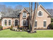 Charming brick home featuring a manicured lawn and arched windows, offering timeless appeal at 9360 Nesbit Lakes Dr, Alpharetta, GA 30022