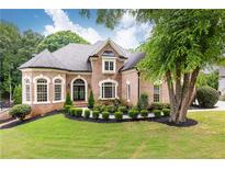 Charming brick home featuring a well-manicured lawn and lush landscaping at 9360 Nesbit Lakes Dr, Alpharetta, GA 30022