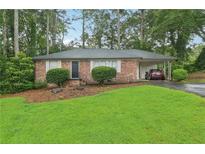 Charming brick home featuring a well-manicured lawn and lush landscaping, complete with an attached carport at 1849 Clay Sw Rd, Mableton, GA 30126