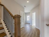 Inviting hallway features light hardwood floors, access to a white-framed front door, and a staircase with decorative trim at 1980 Deco Dr, Kennesaw, GA 30144