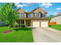 Charming two-story brick home featuring a well-manicured lawn and a two-car garage at 7434 Absinth Dr, Atlanta, GA 30349