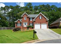Charming two-story red brick home with a well-manicured lawn, mature trees, and two-car garage at 1703 Rifle Sw Rdg, Marietta, GA 30064