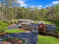 Stately brick home with mature landscaping, circular driveway, and attached garage offers classic elegance at 860 Crest Valley Dr, Sandy Springs, GA 30327