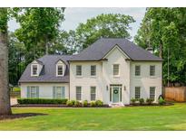 Elegant white brick home featuring a well-manicured lawn and charming blue shutters nestled among mature trees at 2735 Jims Ne Rd, Marietta, GA 30066