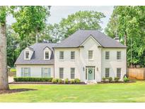 Stately two-story home with a crisp white exterior, complemented by a lush green lawn and mature trees at 2735 Jims Ne Rd, Marietta, GA 30066