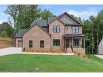 Charming two-story brick home featuring a landscaped yard and covered front porch at 6120 Hutchins Dr, Buford, GA 30518