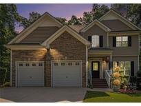 Charming two-story home featuring a stone facade and a two-car garage, set against a backdrop of mature trees at 7052 Camp Falls Ct, Winston, GA 30187