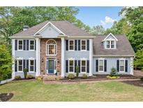 Charming two-story home with blue exterior, manicured lawn, mature trees, and traditional architectural details at 1039 Avery Creek Dr, Woodstock, GA 30188