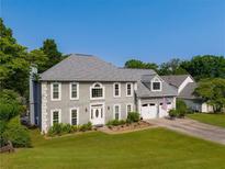 Charming two-story home featuring a manicured lawn, a two-car garage, and a classic gray facade with white trim at 5223 Willow Ridge Dr, Woodstock, GA 30188