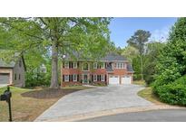 Inviting two-story red brick home featuring a two-car garage and a long driveway at 3130 Crestmont Nw Way, Kennesaw, GA 30152