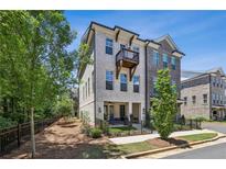 Charming townhome showcasing a light brick facade, balcony, and a manicured front yard with black metal fencing at 408 Townly Ct, Alpharetta, GA 30009