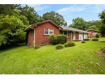 Charming brick home with a well-manicured lawn and mature trees providing shade and curb appeal at 5343 Crystal Ln, Atlanta, GA 30349