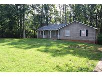 Charming single-story home with a gray exterior and a well-manicured front lawn surrounded by lush trees at 157 Sequoyah Cir, Canton, GA 30115