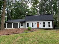 Charming single-story home with a two-car garage, orange front door, and a well-maintained lawn with mature trees at 4617 Cedar Park Dr, Stone Mountain, GA 30083