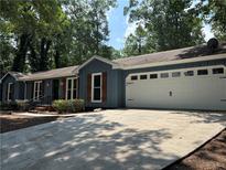 Charming single-story home with blue siding, a large garage, and a well-maintained front yard at 1743 Moss Dr, Snellville, GA 30078