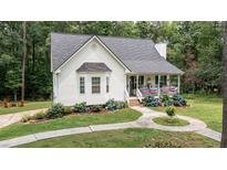Charming home boasts a welcoming porch and landscaped front yard with mature trees and beautiful blue hydrangeas at 10 Stagg Trce, Social Circle, GA 30025